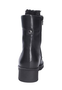 Stivaletto in pelle nera con punta tonda, chiusura con cerniera laterale e morbido rivestimento in pelliccia sul bordo superiore. Tacco piatto, finitura liscia e accentuazione metallica.