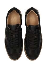 Zapatillas negras que combinan cuero y gamuza. Acabado suave con paneles texturizados, cordones redondos y una suela de goma marrón clara.