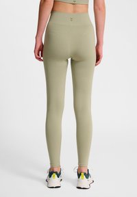 Höga leggings i ljusgrön tyg, med en slät yta och en åtsittande design. Utsmyckade med en subtil logga vid midjan.