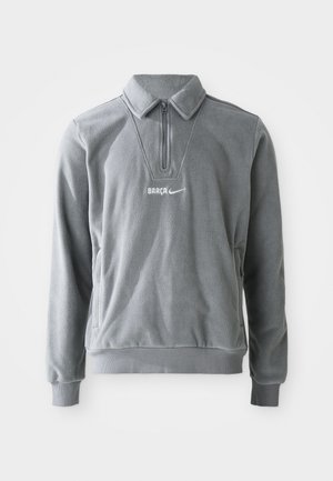 Grijze fleece pullover met een halve rits, kraag en zijzakken. Bevat "BARCA" en het Nike-logo in witte stiksels. Textuur oppervlak.