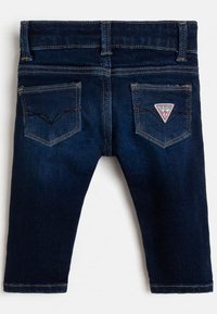 Tummansinisiä farkkuja suoremalla leikkauksella, joissa on kaksi takataskua, joista toisessa on kolmiotunnus ja rinnakkaisompeleet saumoissa.