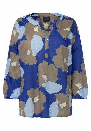 Tunic floreale blu con grandi motivi beige e azzurri. Materiale in cotone, maniche lunghe, scollatura a V e un design rilassato.