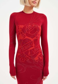 Vestido rojo de manga larga con un patrón floral y el texto "AMOR ETERNO". Tejido suave, silueta ajustada, con puños con orificio para el pulgar para un detalle adicional.