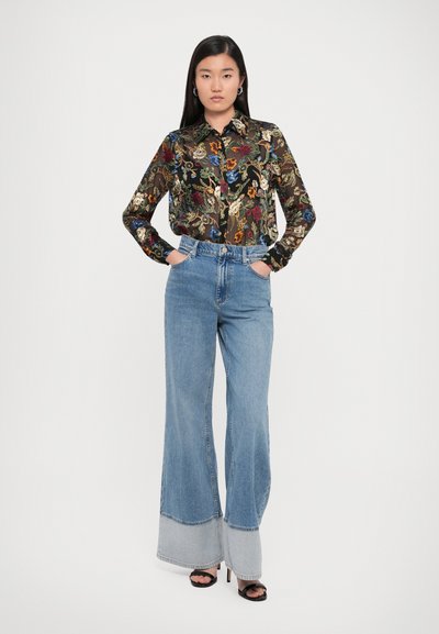 Black floral pattern shirt with long sleeves and button front, paired with high-waisted, light blue wide-leg jeans and black heels.