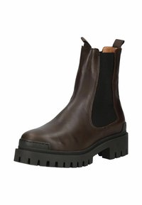 Hnědé kožené Chelsea boty s elastickými bočními panely, silnou černou gumovou podrážkou, zaoblenou špičkou a výrazným švem.