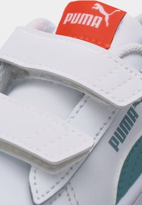 Λευκό αθλητικό παπούτσι Puma με τιρκουάζ λωρίδα, δύο λευκές λουρίδες με βέλκρο και κόκκινο λογότυπο Puma στη γλώσσα.