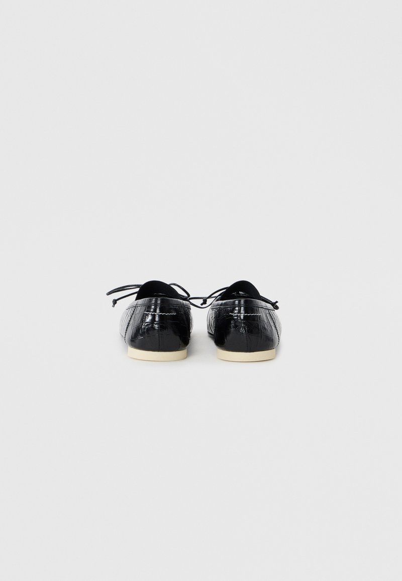 Black patent leather ballet flats with a textured, crocodile pattern and thin laces. White rubber soles with minimal heel.