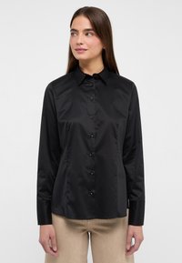 Schwarze Hemdjacke aus glattem Stoff mit klassischem Kragen, langen Ärmeln und taillierter Passform sowie schwarzen Knöpfen.