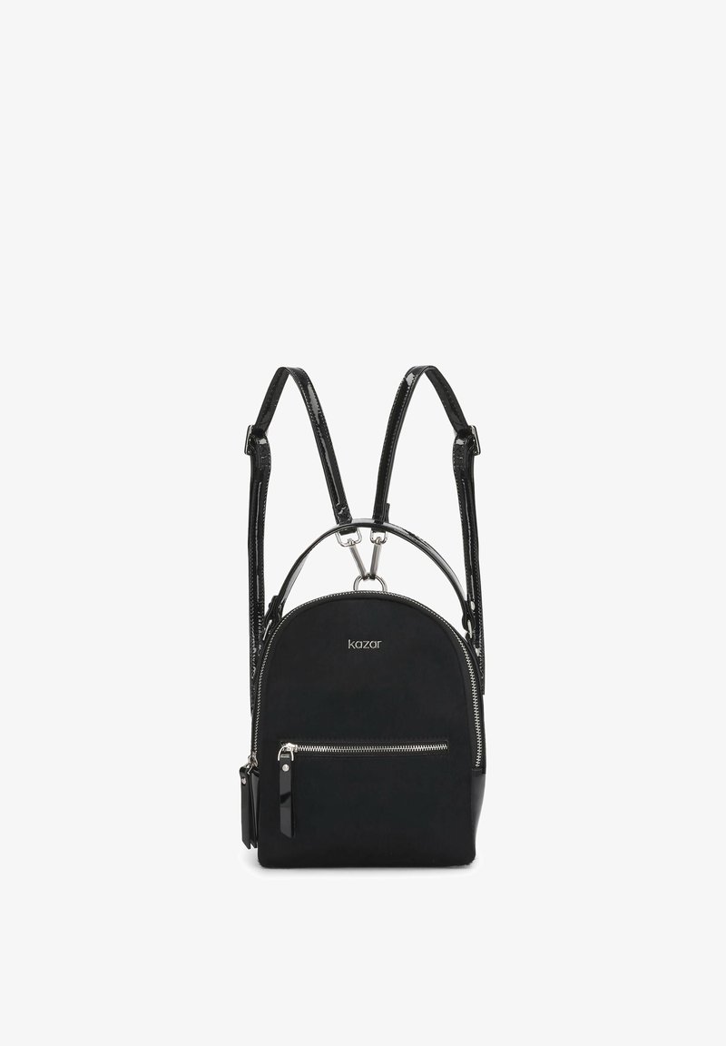Sac à dos Kazar noir avec poche zippée argentée, bretelles brillantes réglables et petite poignée supérieure sur fond blanc.