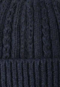 Bonnet en tricot navy foncé, doté d'un motif côtelé texturé et de fibres de fil visibles, avec un revers replié en bas.