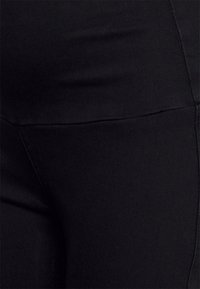 Leggings pretos elásticos com uma textura suave e um design ajustado, apresentando uma cintura larga e detalhes de costura mínimos.