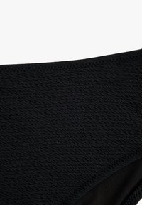 Tessuto da bagno nero con un motivo testurizzato e ondulato. Bordature lisce e design senza cuciture, che mettono in mostra un materiale morbido e elastico.