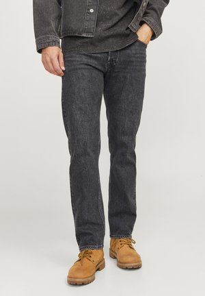 Jeans de denim gris oscuro con corte recto, combinados con botas de trabajo color beige. Los jeans presentan una textura sutil y detalles de costura.
