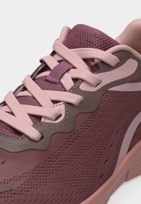 Gros plan sur une chaussure de sport rose et mauve avec une tige en maille texturée, des lacets rose clair et un col rembourré pour un meilleur maintien.