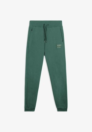 Joggers de lana polar verdes con cintura elástica, cordón, bolsillos laterales con cremallera y branding impreso en el muslo izquierdo.
