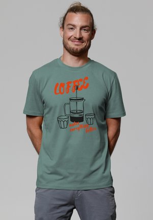 Green cotton t-shirt with red text “COFFEE makes everything better” and graphic of a coffee pot and two cups. Casual fit.