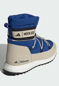 Blå och beige vinterkänga med vadderad krage, kontrasterande texturer, snören och märkesrem. Gummisula med greppande mönster.