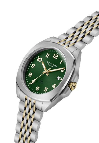 Ceas metalic argintiu și auriu cu cadran verde, cifre și ace aurii, fereastră pentru dată la ora 3, și branding "rag & bone" pe față.