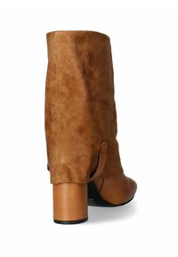 Stivale alla caviglia in suede marrone con punta rotonda, tacco quadrato e dettagli laterali. Presenta una consistenza morbida e un design a bassa apertura sul retro.