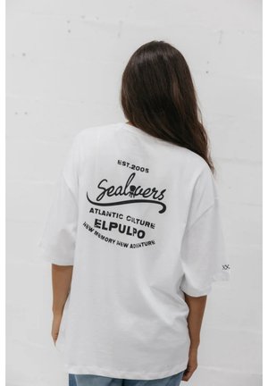Camiseta blanca de gran tamaño con texto impreso en negro en la parte trasera: "Sealovers", "Atlantic Culture", "Elpulpo" y "Est. 2005". Corte holgado.