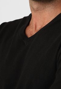 Czarny sweter dzianinowy z dekoltem w szpic, z miękką teksturą i prążkowanymi detalami przy kołnierzu, podkreślający czyste linie i prostotę.