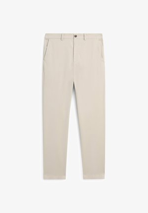 Beżowe spodnie o wąskim kroju z szlufkami na pasek, frontowym zapięciem na guzik i zamek błyskawiczny oraz bocznymi kieszeniami, prezentowane na płasko na białym tle.