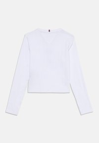 T-shirt blanc à manches longues avec un design court, un tissu texturé, un décolleté en V et de petites touches de logo à l'arrière.