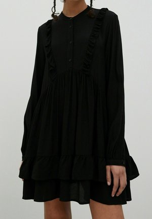 Schwarzes Langarmkleid mit Rüschendetails, Knopfverschluss und ausgestelltem Saum. Hergestellt aus leichtem Stoff mit strukturierter Oberfläche.