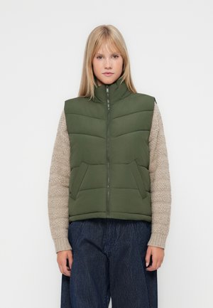 Groene puffer vest met hoge kraag, geborduurd ontwerp en voorzakken, gecombineerd met een beige textuursweater en marineblauwe gestreepte broek.