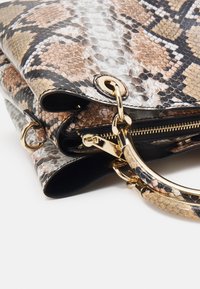 Sac à main à imprimé serpent combinant des textures beige, noire et blanche, avec des éléments métalliques dorés et une poche zippée.
