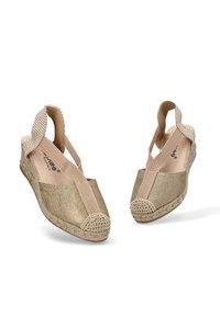 Zapatos de espadrilles tejidos en oro con un diseño de tira detrás, presentando un empeine texturizado, suela de yute trenzado y punta redondeada.