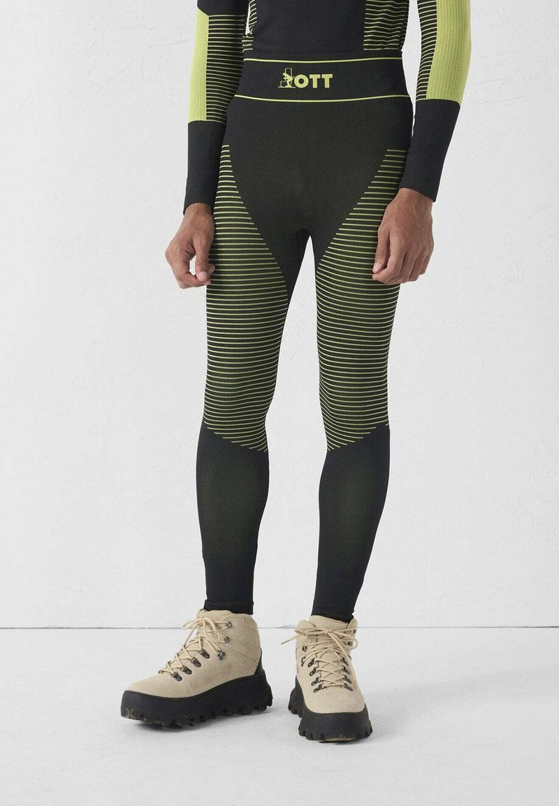 Zwart met neon groene gestreepte wetsuit-broek met een hoge tailleband, voorzien van een aansluitend ontwerp en een zachte textuur, gecombineerd met beige wandelschoenen.