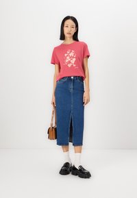 Rosa grafisk t-shirt med blommönster, tillsammans med en denim midi-kjol med en framtill slit. Svarta platåskor och en brun handväska fulländar outfiten.