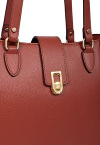 Borsa a mano in pelle marrone con texture, dotata di hardware dorato, con forma strutturata e doppi manici, che presenta un dettaglio di chiusura a patta.