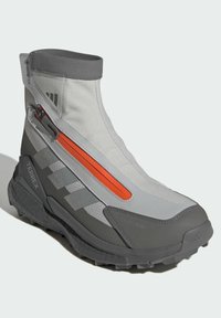 Gray waterproof boot with a high ankle, featuring a gray and orange zip. Textured upper, rubber sole with deep tread pattern for traction.
