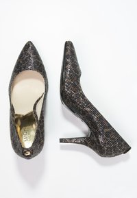 Chaussures à talons hauts noires et bronze avec un bout pointu, un motif texturé et une finition brillante. Elles possèdent un talon stiletto élancé.
