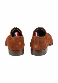 Bruine suède schoenen met een gladde textuur, lage hak, ronde neus en contrasterende voering met een rood, wit en blauw gestreept accent.