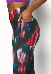 Hög midja leggings i ett flerfärgat abstrakt mönster. Tillverkade av stretchtyg med en jämn yta och en sidficka.