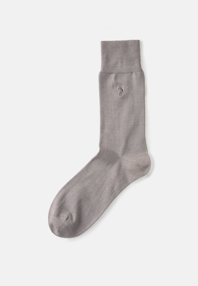 Calcetín gris hasta el tobillo hecho de material suave con un puño acanalado y un pequeño logotipo bordado cerca de la parte superior. Textura suave y color neutro.
