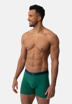 Grønne bomuldsboxershorts med en marineblå elastisk talje, der har en tætsiddende pasform og en glat tekstur. Designet inkluderer en støttende lomme.