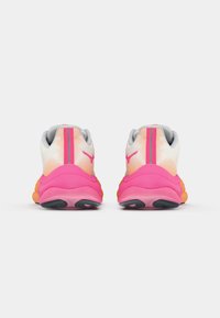 Athletic shoes with a white mesh upper, pink accents, and a thick, multi-colored sole. Features a textured design and a logo on the heel.