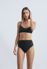 Sort bh og højtaljede briefsæt lavet af blødt stof, med tynde stropper og en mærkevare-linning, præsenteret mod en neutral baggrund.