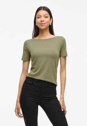 Camiseta de manga corta color verde oliva en un estilo ajustado con un escote ancho, combinada con jeans negros de tiro alto, que presentan una textura suave.