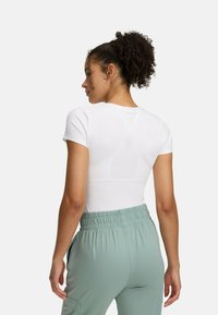 White fitted t-shirt with short sleeves, paired with mint green elastic-waist joggers. Smooth fabric with subtle sheen and no visible logos.