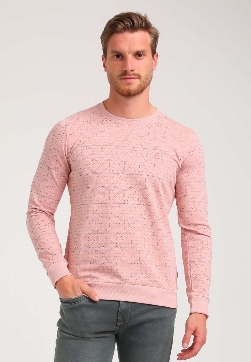 Sudadera rosa clara con un patrón geométrico en azul. Presenta un cuello redondo, mangas largas y puños y dobladillo acanalados. Textura de tela suave.