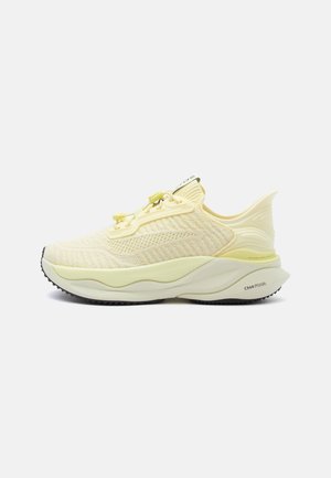 Chaussure de course coussinée jaune clair avec tige en maille, semelle épaisse, lacets à bascule et semelle extérieure texturée noire, vue latérale sur fond uni.