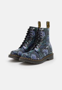 Zwarte veterschoenen met bloemenprint, glossy afwerking, blauwe en groene patronen, gele stiksels en zwarte rubberen zolen.