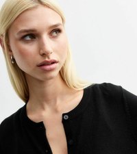 Cardigan nero con colletto rotondo, caratterizzato da una texture liscia e chiusura frontale a quattro bottoni. Il modello presenta un trucco neutro e capelli biondi.