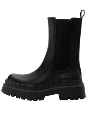 Bottine Chelsea en cuir noir avec semelle épaisse crantée, panneaux latéraux élastiques et languette à l'arrière.