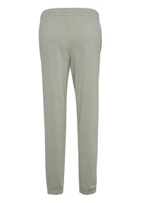 Ljusgrå joggers i mjukt tyg, med elastisk midja och elastiska muddar vid anklarna, designade för komfort och lätthet.